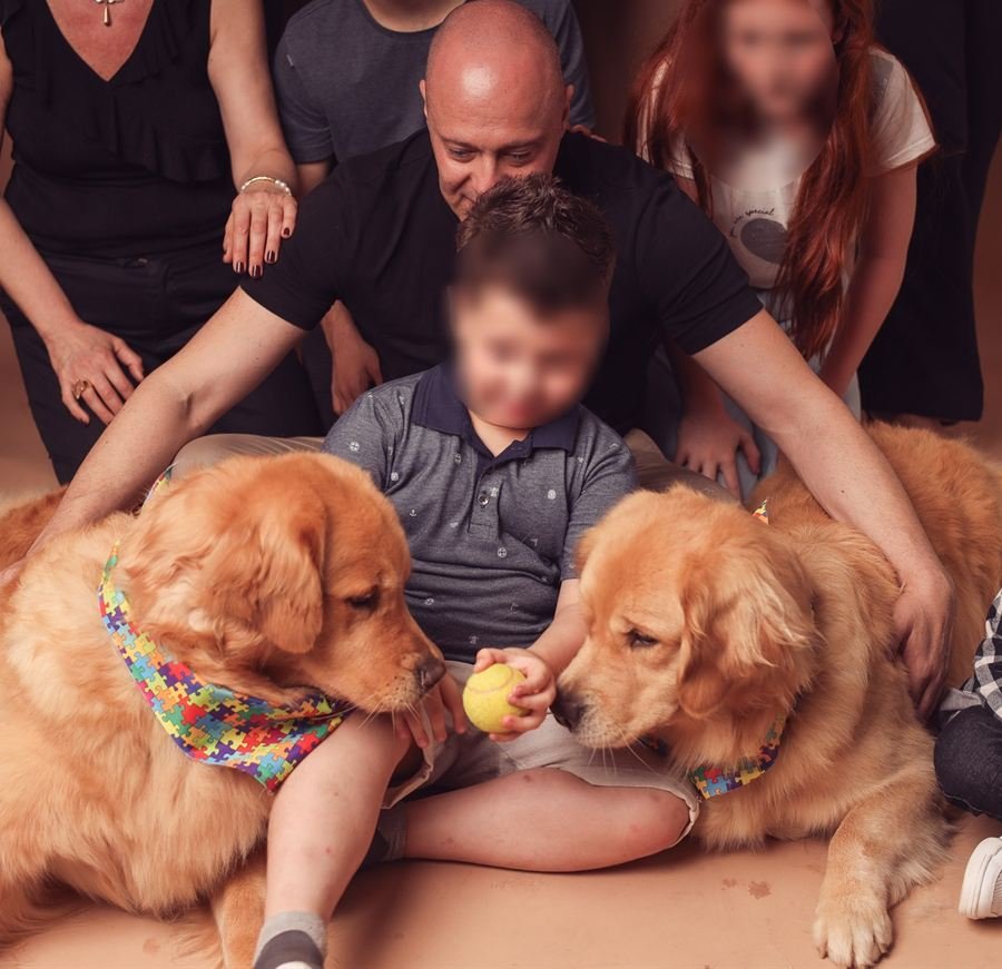 O psicólogo Diógenes Corteletti acompanha uma criança entre as duas cadelas de terapia, que usam bandanas com a estampa de quebra-cabeça do autismo, em atendimento na Clínica Zuccari, em Novo Hamburgo